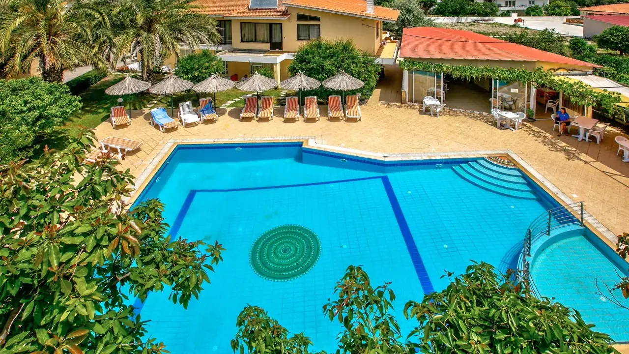 Basen hotelowy na Rodos, z leżakami i parasolami. Idealne miejsce na relaks pod słońcem.