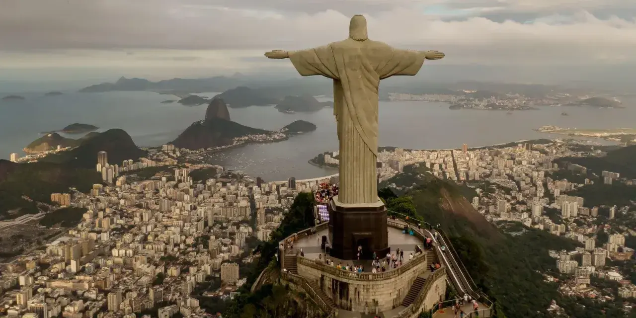 Majestatyczny pomnik Rio de Janeiro Jezus wita turystów, rozpościerając ramiona nad tętniącym życiem miastem i zatoką.