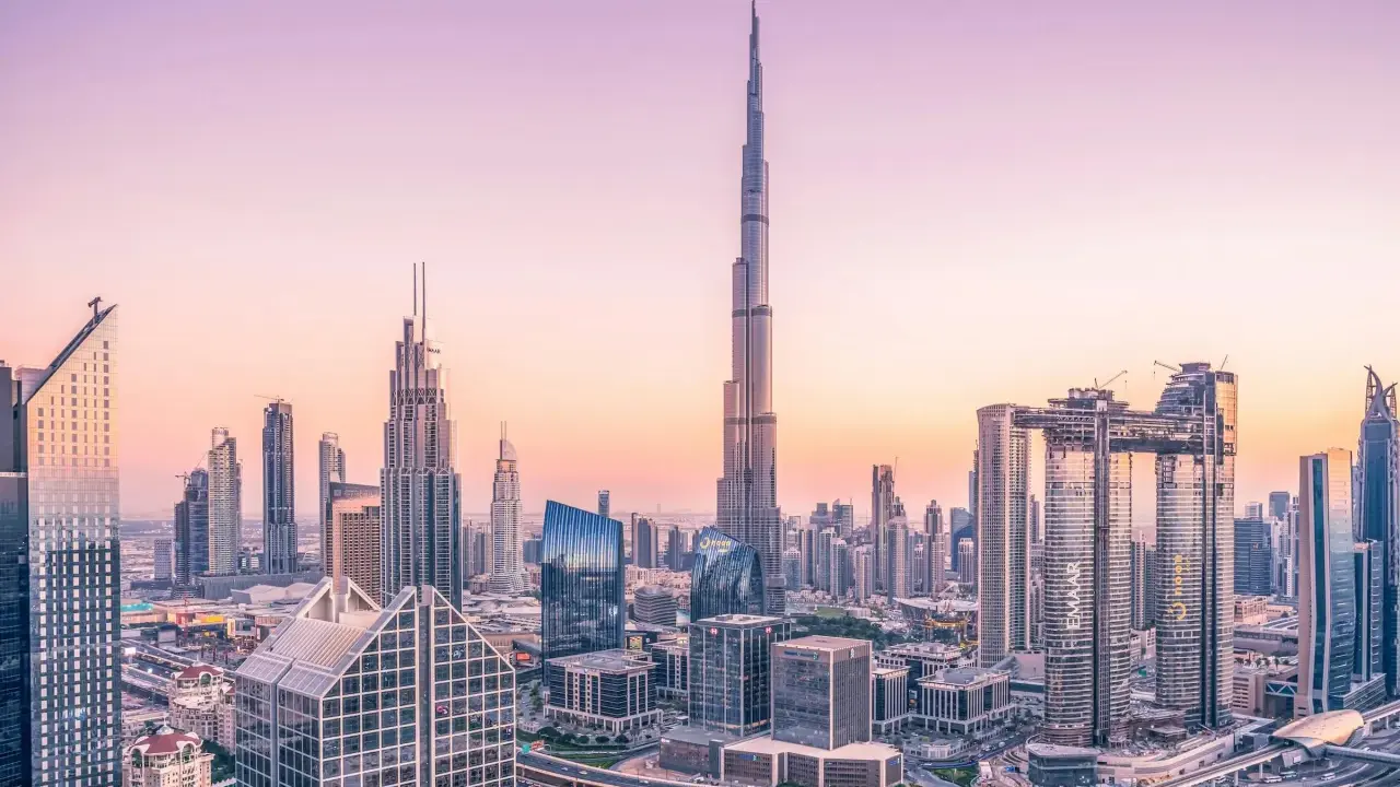 Dubaj o zachodzie słońca, z dominującym Burdż Chalifa, najwyższym budynkiem świata, otoczonym nowoczesnymi wieżowcami i autostradami.