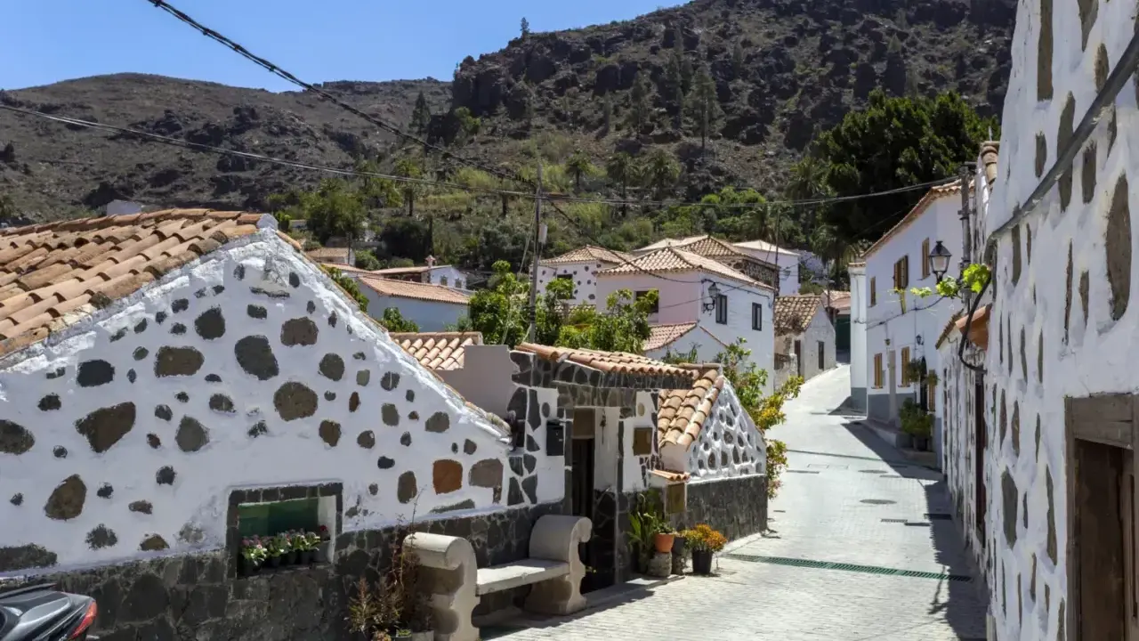 Urokliwa uliczka z białymi domami i kamiennymi zdobieniami na Gran Canarii. Odkryj te i inne **Gran Canaria atrakcje**!