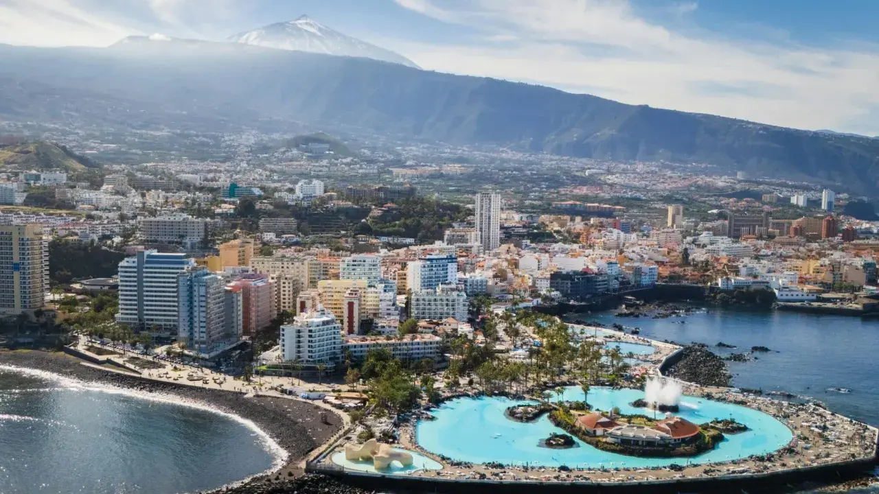 Puerto de la Cruz atrakcje: Lago Martianez, baseny z wodą morską, plaża, miasto i wulkan Teide w tle.