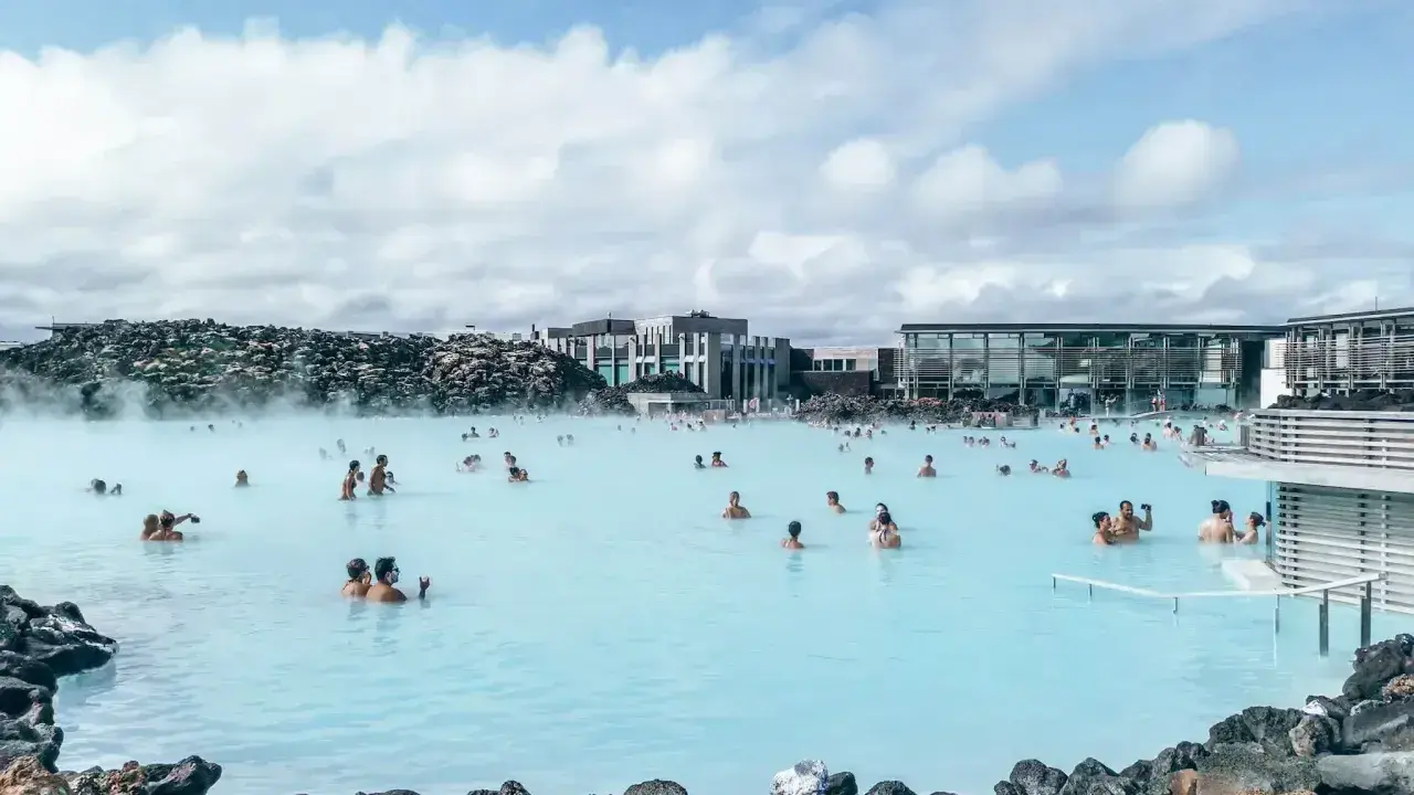 Relaks w Blue Lagoon Islandia. Ludzie kąpią się w mlecznoniebieskiej wodzie geotermalnej otoczonej wulkanicznymi skałami.