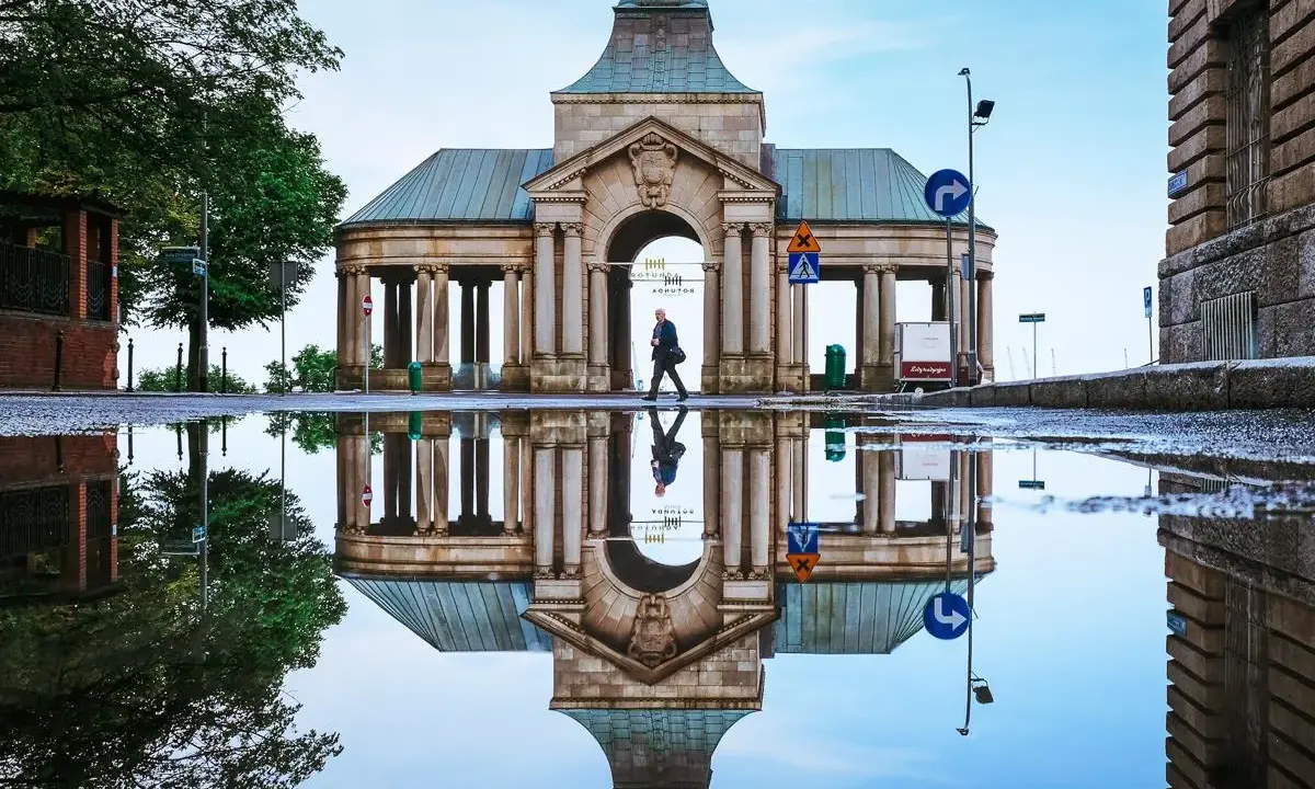 Odbicie zabytkowej budowli w kałuży, tworzące surrealistyczny widok. Nietypowe atrakcje Szczecin w deszczowy dzień.