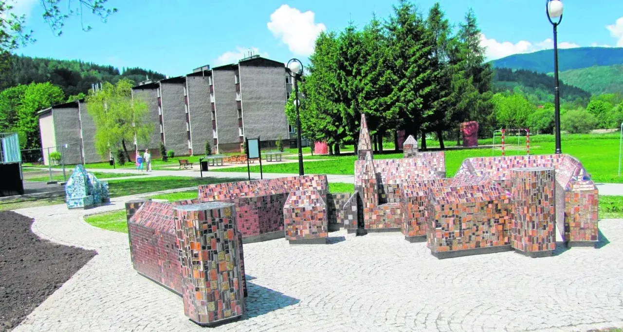Miniatury budowli z mozaiki, ciekawe wisła atrakcje turystyczne. W tle budynki mieszkalne i zalesione wzgórza.