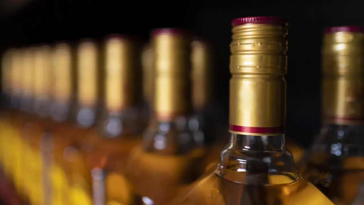 Rząd butelek z alkoholem, z złotymi zakrętkami. Czy to zapasy przed podróżą do Hiszpanii, gdzie obowiązuje limit alkoholu?