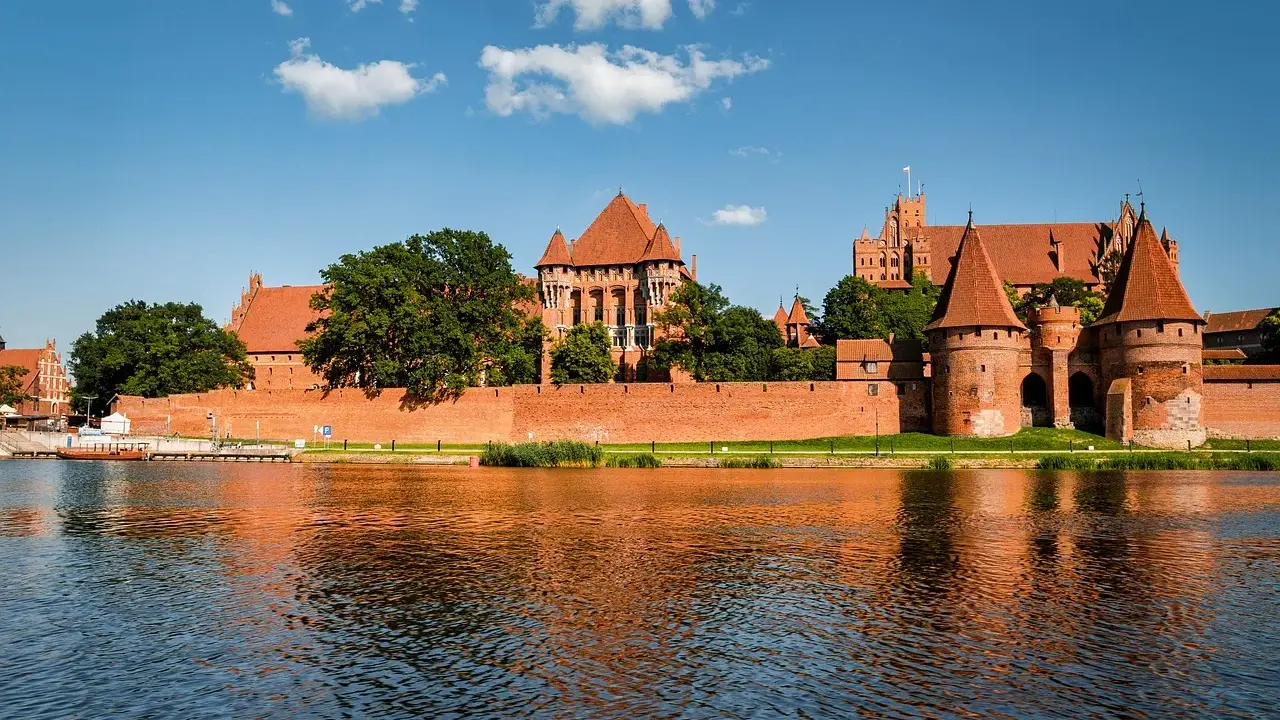 Potężny zamek w Malborku odbija się w wodzie. Zastanawiasz się, ile trwa zwiedzanie zamku w Malborku?
