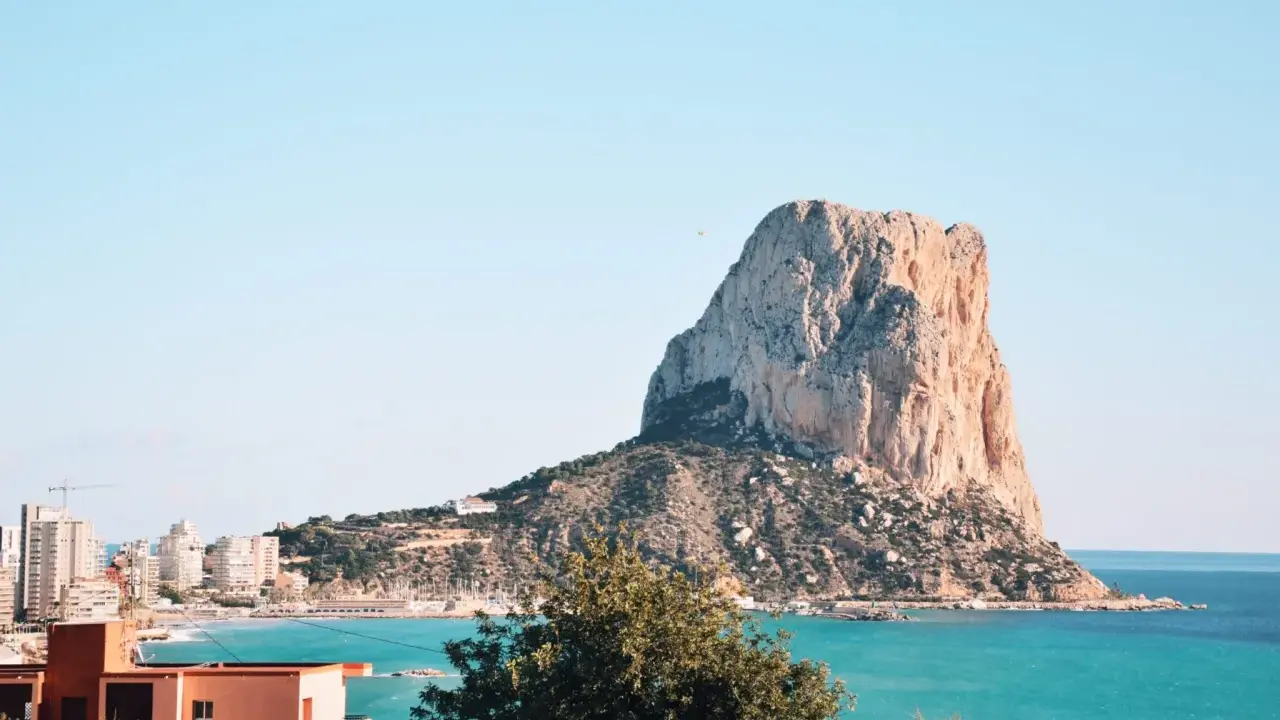 Imponujący klif Peñón de Ifach, jedna z głównych atrakcji Costa Blanca, góruje nad turkusowym morzem i nadmorskim miasteczkiem.