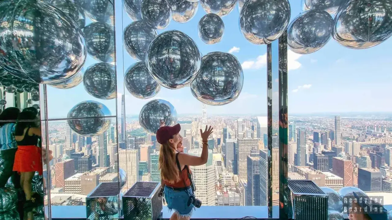 Kobieta cieszy się widokiem z Summit One Vanderbilt, otoczona lśniącymi kulami.