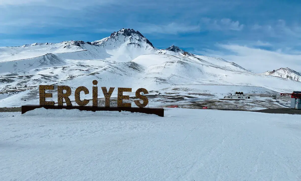 Zimowy krajobraz z napisem "ERCIYES" na tle ośnieżonych gór. Idealne miejsce na narty w Erciyes Ski Resort.