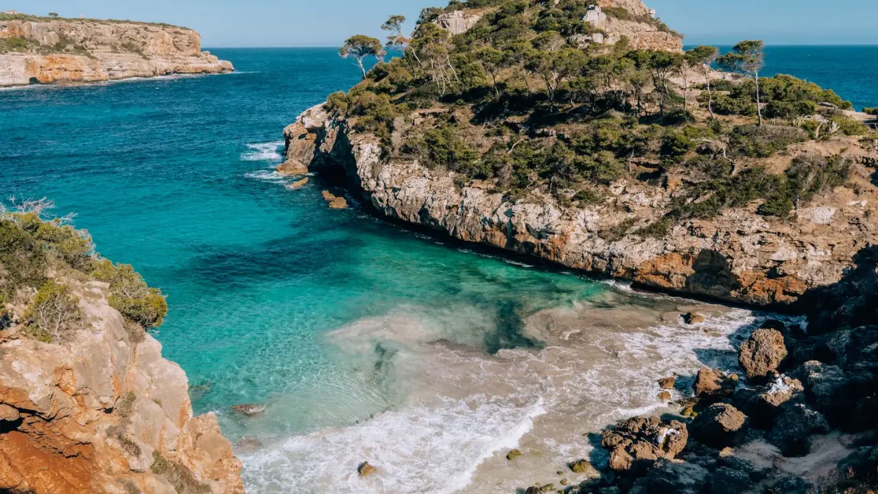Malownicze wybrzeże z turkusową wodą i skalistymi klifami, idealne miejsce na wakacje na Palma de Mallorca.