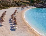 Rządki parasoli i leżaków na kamienistej plaży, obok krystalicznie czystej, turkusowej wody. To jedna z najpiękniejszych plaż w Europie, idealna na relaks.
