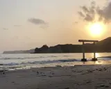 Zachód słońca nad spokojnym morzem, z bramą torii na plaży w Japonii.