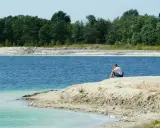 Samotny mężczyzna siedzi nad turkusową wodą, która przypomina polskie Malediwy łódzkie.