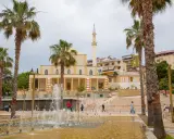 Plac z fontannami i palmami przed meczetem w Durrës, Albania. Ludzie spacerują po schodach.