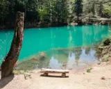Niesamowite kolorowe jeziorka otoczone lasem. Drewniana ławka zaprasza do odpoczynku nad turkusową wodą.