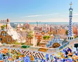 Kolorowe mozaiki i bajkowe budowle w Parku Güell z widokiem na Barcelonę.