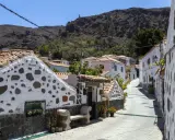 Urokliwa uliczka z białymi domami i kamiennymi zdobieniami na Gran Canarii. Odkryj te i inne **Gran Canaria atrakcje**!