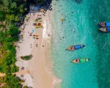 Rajska plaża na tajlandzkiej wyspie Phuket. Kajaki czekają na plaży, a turyści kąpią się w turkusowej wodzie.