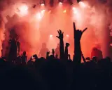 Tłumy na jednym z corocznych festiwali w Polsce, wznoszą ręce w górę, otoczone dymem i czerwonym światłem sceny.