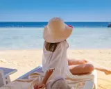 Dziewczynka w kapeluszu na plaży, marząca o tym, gdzie warto polecieć. Piękne morze i słońce zachęcają do odpoczynku.