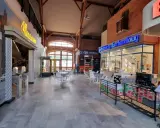 Wnętrze z neonami "Muzeum" i "Spółdzielczy dom handlowy". Atrakcje w Zamku Topacz to m.in. sklepiki i kawiarnia.