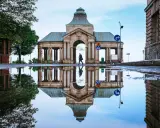 Odbicie zabytkowej budowli w kałuży, tworzące surrealistyczny widok. Nietypowe atrakcje Szczecin w deszczowy dzień.