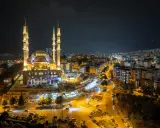 Piękny meczet nocą, oświetlony i otoczony miastem. Warto wiedzieć, ramadan co to za święty czas.