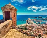 Alicante co zobaczyć: widok z zamku na port, plażę i miasto. W oddali statki wycieczkowe.