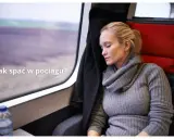 Kobieta odpoczywa, śpiąc w pociągu. Obok niej butelka wody, a za oknem rozmyty krajobraz.