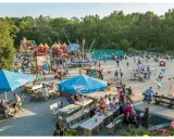 Rodzinna zabawa na placu zabaw w Ocean Park Władysławowo. Dzieci szaleją na dmuchanych zamkach, trampolinach i zjeżdżalniach, podczas gdy dorośli odpoczywają przy stolikach.