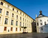 Zamek na Hradczanach, z jego długą, kremową fasadą i okrągłą, białą kaplicą, prezentuje się majestatycznie pod błękitnym niebem.
