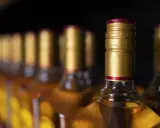 Rząd butelek z alkoholem, z złotymi zakrętkami. Czy to zapasy przed podróżą do Hiszpanii, gdzie obowiązuje limit alkoholu?