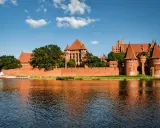 Potężny zamek w Malborku odbija się w wodzie. Zastanawiasz się, ile trwa zwiedzanie zamku w Malborku?