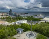Gdynia co zobaczyć: pomnik z różą wiatrów i krzyżem na wzgórzu, w tle port, plaża i drapacze chmur.