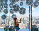 Kobieta cieszy się widokiem z Summit One Vanderbilt, otoczona lśniącymi kulami.