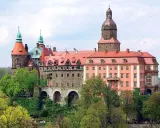 Malownicze zamki i pałace wokół Wrocławia, jak ten imponujący kompleks z wieżami i czerwonymi dachami, zachwycają architekturą i otoczeniem.
