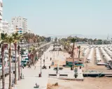 Promenada w Larnace z palmami, białymi budynkami i plażą pełną leżaków. Idealne miejsce, by zobaczyć, co oferuje Larnaka.