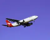 Samolot Qantas z charakterystycznym kangurem na ogonie, symbolizujący najbezpieczniejsze linie lotnicze, leci na tle błękitnego nieba.