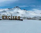 Zimowy krajobraz z napisem "ERCIYES" na tle ośnieżonych gór. Idealne miejsce na narty w Erciyes Ski Resort.