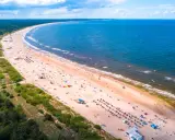 Słoneczne plaże w Polsce tętnią życiem. Tłumy ludzi odpoczywają na piaszczystym brzegu, kąpią się w morzu i cieszą się wakacjami.
