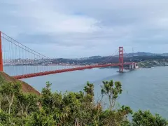 Widok na most Golden Gate w San Francisco, z zielonymi wzgórzami i błękitną wodą.