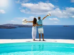 Para, którzy szukają, gdzie najcieplej w kwietniu, idealne miejsce to Santorini. Para cieszy się widokiem na morze z basenu.