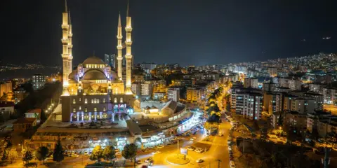 Piękny meczet nocą, oświetlony i otoczony miastem. Warto wiedzieć, ramadan co to za święty czas.