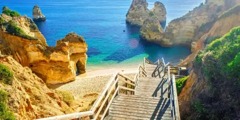Malownicze schody prowadzą do ukrytej plaży z turkusową wodą, otoczonej klifami. Idealne miejsce na wakacje w portugalskich miastach turystycznych.
