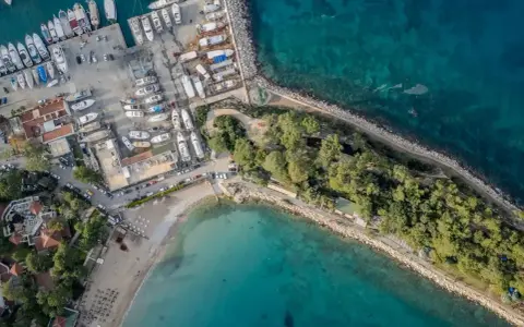 Widok z lotu ptaka na port i plażę w Kemerze. Widać liczne jachty i łodzie, a także zielony teren z drzewami. To idealne miejsce na odkrywanie atrakcji Kemer Turcja.