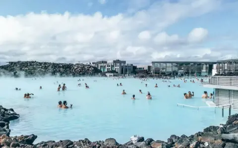 Relaks w Blue Lagoon Islandia. Ludzie kąpią się w mlecznoniebieskiej wodzie geotermalnej otoczonej wulkanicznymi skałami.
