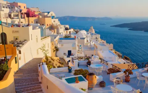 Piękne białe domy Santorini z widokiem na błękitne morze. Idealna pogoda na krecie, by podziwiać krajobraz.
