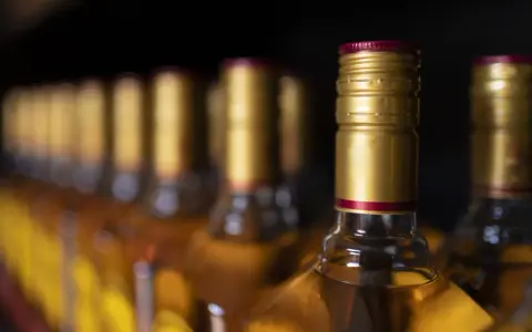 Rząd butelek z alkoholem, z złotymi zakrętkami. Czy to zapasy przed podróżą do Hiszpanii, gdzie obowiązuje limit alkoholu?