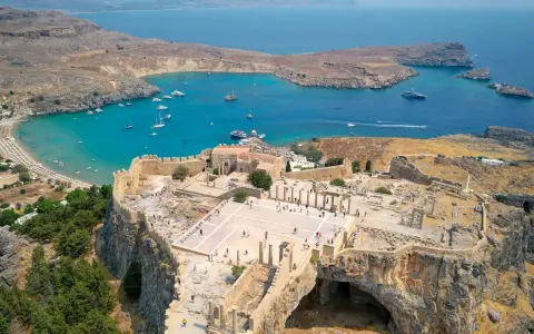 Akropol w Lindos na Rodos, z widokiem na turkusową zatokę i plażę. Wspaniałe ruiny przypominają o dawnej świetności, a nie o koszmarze.