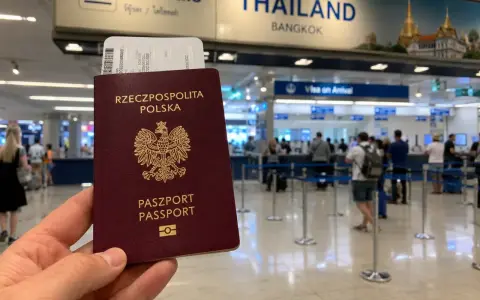 Polski paszport i bilet lotniczy w ręku, w tle tablica "THAILAND BANGKOK" i stanowiska "Visa on Arrival". Sprawdzanie tajlandia warunki wjazdu.